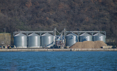 Obraz premium Silos for grains and piles of sand on the banks of the Danube