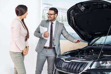 Vehicle salesman presenting new cars at showroom
