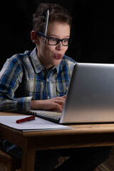 Boy funny on PC with tongue out on laptop