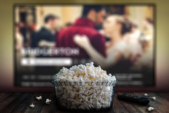 Video streaming app on tv screen behind a bowl of popcorn and a remote control.	