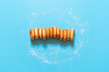Donuts in a row on blue background. Homemade ring doughnuts, top view