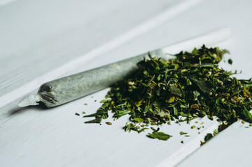 Chop the marijuana and marijuana joint on a wooden table . Weed and Ganja-joint cigarette.close-up