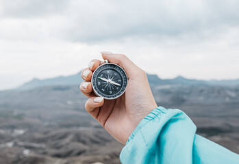 Compass in hand in the first person. Travel symbol. Against the background of mountain nature. - 403851280