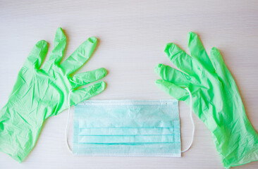 Green medical gloves and medical mask on a light wooden background. Medical supplies the Covid19 epidemic. Hygiene, coronavirus, health concept. Medical supplies for doctors.