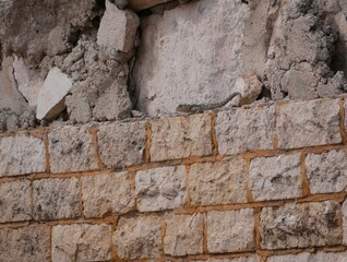 A large gray-brown lizard sits in the summer on a ruined fence of stones and concrete. Mountain agam basks in the sun on a hot summer day.