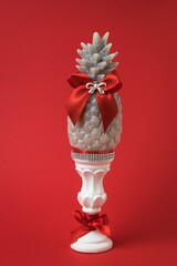 Hand with a decorative candle in the shape of a pineapple on a red background.