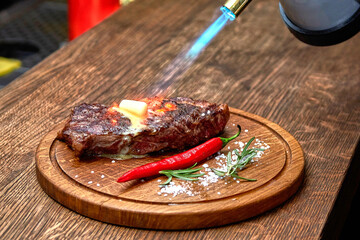 Master chef cooking barbecue Beef Grilled steak meat with fire flames on wooden table