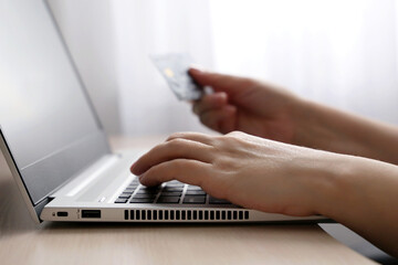 Woman holding credit card types on laptop keyboard. Concept of online shopping and payment, financial transactions