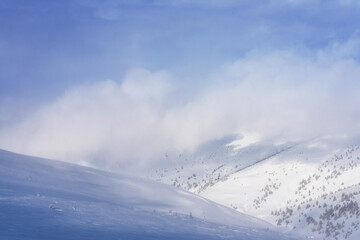 Clouds covering the snowy mountains. Winter landscape.