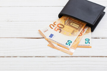 euro  in  black wallet on white wooden background
