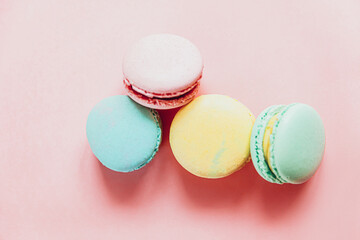 Sweet almond colorful pink blue yellow green macaron or macaroon dessert cake isolated on trendy pink pastel background. French sweet cookie. Minimal food bakery concept. Flat lay top view, copy space
