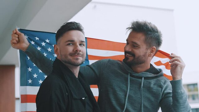 Happy gay male couple holding usa flag. High quality 4k footage