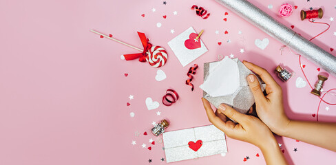 Female hands hold a love letter in an envelope, mock up . The process of decorating a gift for Valentine's Day.Festive banner with copy space, top viev.