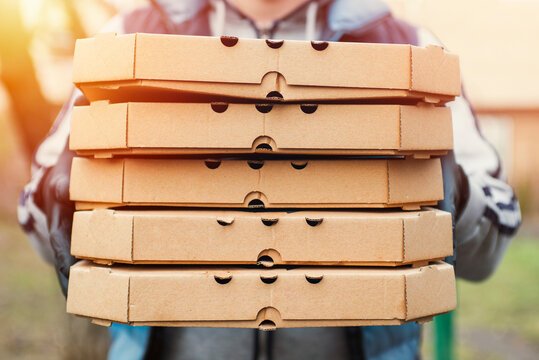 Man delivering pizza. A Deliveryman is holding a large stack of pizza boxes. Pizza delivery man delivering pizzas to a house