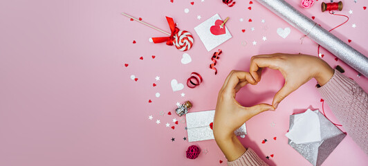 . Woman forming shape of heart with her fingers. The process of decorating a gift for Valentine's Day.Festive banner with copy space, top viev.