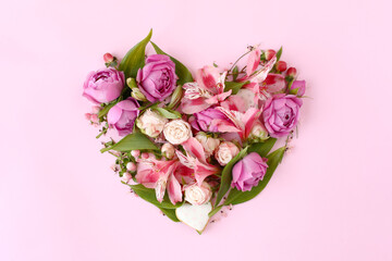 Heart shaped floral composition on pink background.