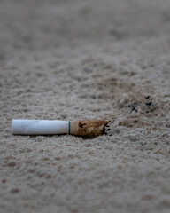 Balneário Gaivota, Santa Catarina, Brazil, January 2021. A cigarette thrown in the sand by the sea with a marked trail polluting the environment.