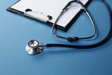 Stethoscope and tablet for recording patients on blue background