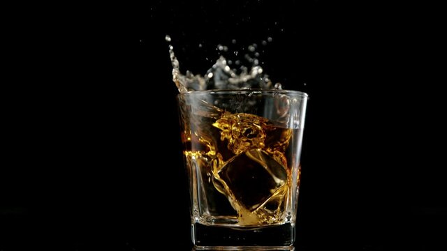 Super slow motion of falling ice cube into whiskey drink. Filmed on high speed cinema camera, 1000 fps.