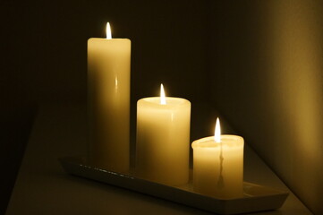 Fototapeta na wymiar Three candles burning in the dark