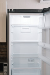 Empty open white refrigerator in the kitchen.