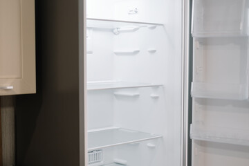 Fototapeta premium Empty open white refrigerator in the kitchen.