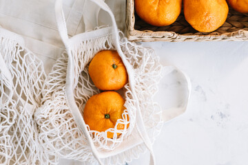 Fresh oranges in eco net shopping bag on white background.