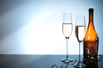 Two glasses of champagne and a bottle on a mirrored bar counter.
