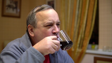 The man eats a hamburger and drinks soda. Man with hamburger at home.