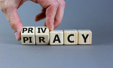 Privacy vs piracy symbol. Businessman hand turns cubes and changes the word 'piracy' to 'privacy'. Beautiful grey background, copy space. Business and privacy vs piracy concept.