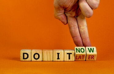 Do it now symbol. Businessman hand turns cubes and changes words 'do it later' to 'do it now'. Beautiful orange background. Business and do it now concept. Copy space.