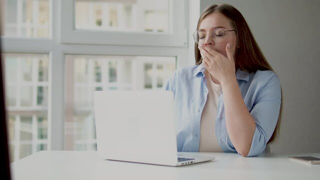 Tired thoughtful woman yawning working on laptop, lack of inspiration and energy