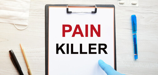 The inscription PAIN KILLER in the form. Doctor in latex gloves points to medical lettering on white letterhead: healthcare concept.