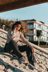 mujer joven adolescente sonriendo sentada en las rocas con color calido de verano.