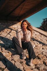 mujer joven adolescente sonriendo sentada en las rocas con color calido de verano.