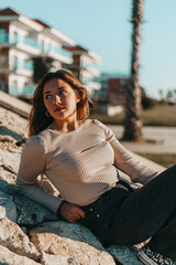 mujer joven adolescente sonriendo sentada en las rocas con color calido de verano.