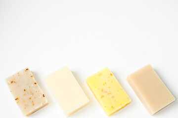 Handmade soap bars in pastel colors on a white background.