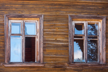 Obraz na płótnie Canvas Facade of a wooden abandoned residential building with broken windows