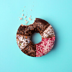 Bitten glazed donut with crumbs on pastel blue background. Creative food concept. Flat lay.