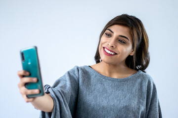 Young woman smiling and reacting to phone, isolated on white studio background