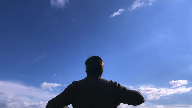 man with his back to the middle plane taking off his mask with a blue sky background