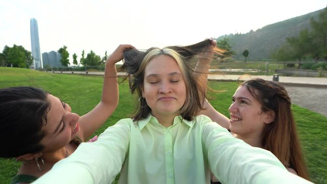 a group of friends trying to take a selfie while her other friends interact with her to get the best picture