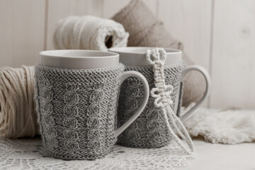 Obraz na płótnie Canvas Teacups in decorative sweaters on light background