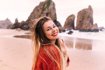 Happy pretty girl walks along the sea coast against the background of the sea and rocks, from...