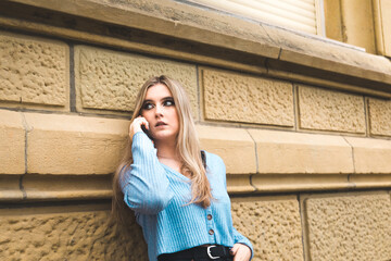 Fototapeta premium Young blonde woman taking by mobile phone on the street