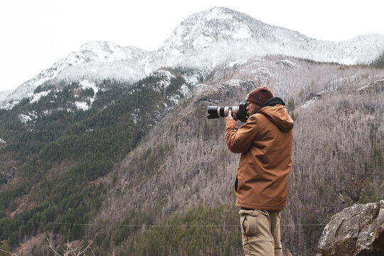 Male photographer holding a DSLR and capturing images of scenic landscape in Washington State