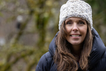 Pretty woman wearing warm hat and puffy jacket outside in nature