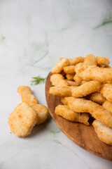 chicken nuggets and chicken tenders, wooden plate with a lot of nuggets. green marmot background