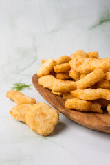 chicken nuggets and chicken tenders, wooden plate with a lot of nuggets. green marmot background