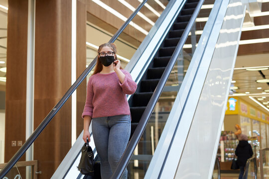 Young white caucasian woman on an escalator wearing face mask